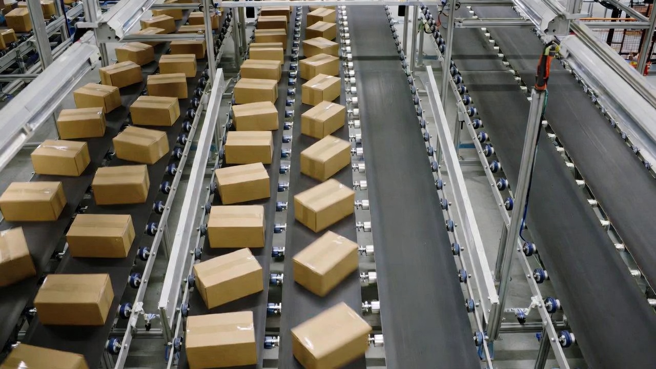 Two parallel conveyor belts viewed from above, one loaded with identical cargo boxes, the other empty.